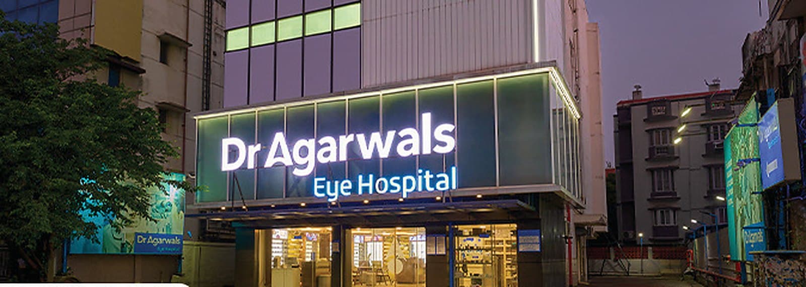 The Dr Agarwals Eye Hospital at Anna Nagar in Chennai at dusk, its illuminated sign above the glazed entrance